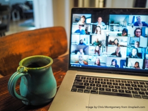 a laptop showing a virtual meeting and a mug on top of a wooden table | source: unsplash.com