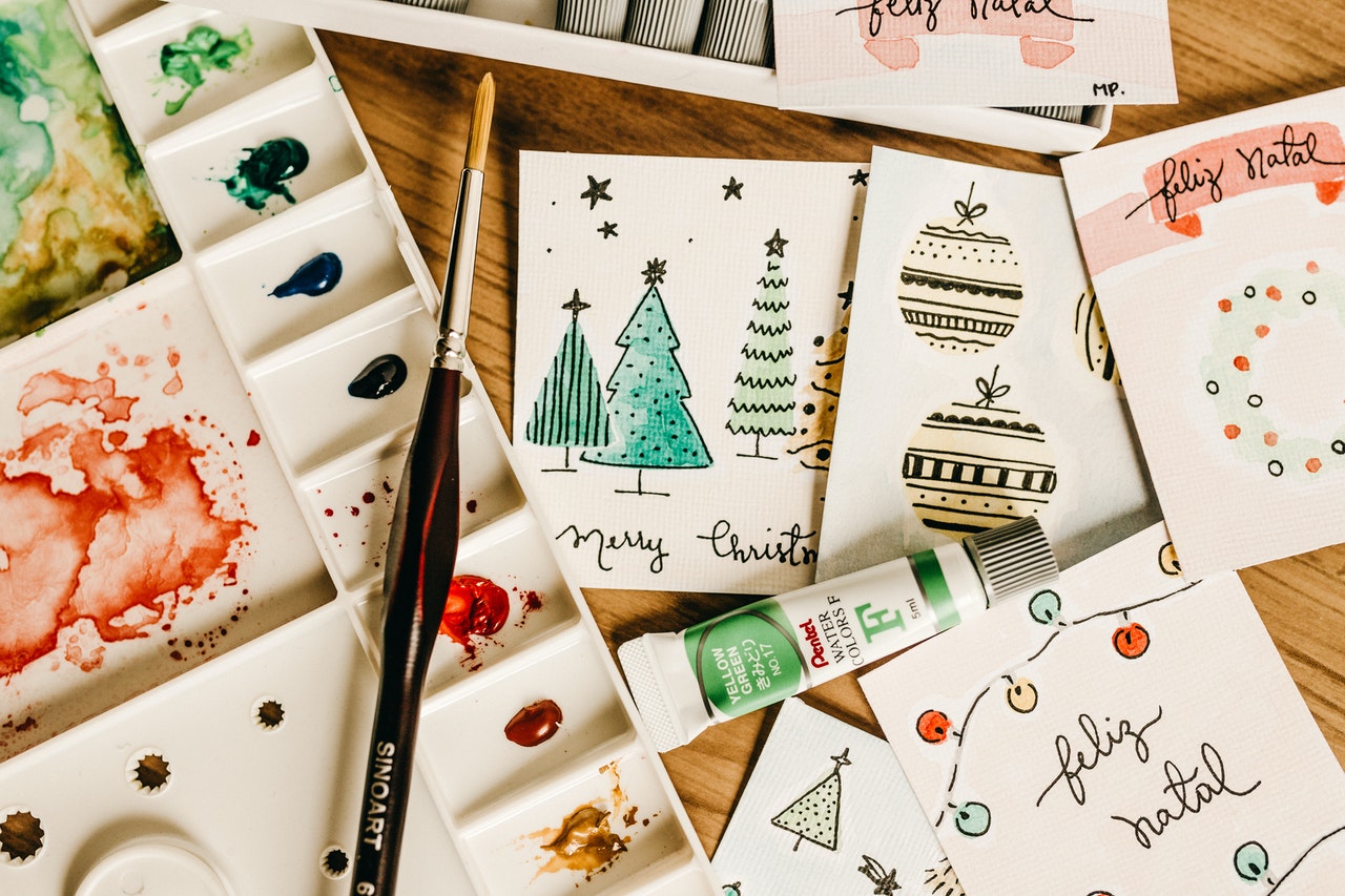 handcrafted Christmas cards and art materials on a table | image source: pexels.com