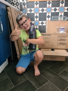 A smiling boy gives a thumb up while holding his "rocket fuel" bottle.