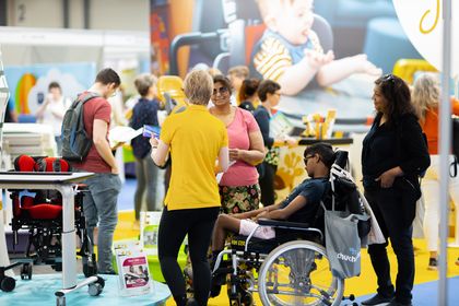 The photo shows families of disabled people, including a boy sat on a wheelchair, at a past Kidz to Adultz exhibition.