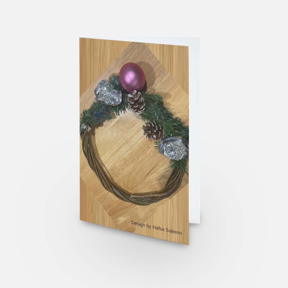The image shows a mock-up of the festive card with Hafsa's design (showing a festive wreath).