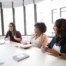 The photo shows a group of people chatting around a table.