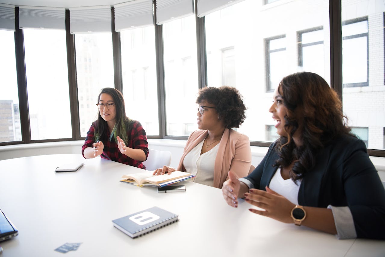 The photo shows a group of people chatting around a table.