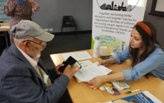 The photo shows Jen from the MPCF team speaking to a Drop-in visitor, with the forum banner behind her, at the Local Offer Drop-in @ Manchester College's Openshaw campus back in October 2023.