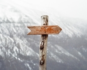 photo of a direction arrow on a pole, pointing right, with a white mountain in the background