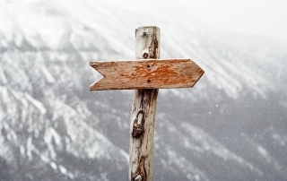 photo of a direction arrow on a pole, pointing right, with a white mountain in the background