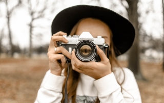 A woman holding a camera | image source: Pexels.com