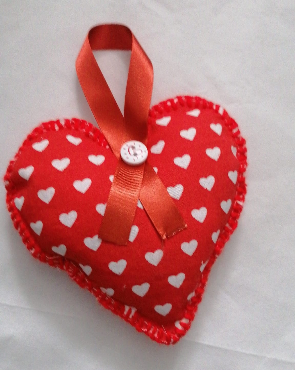 A small, red, heart-shaped pillow dotted with white hearts