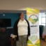 Dawn from our MPCF Team poses beside the MPCF banner, as educational psychologists from One Education speak to parents behind her. This photo was taken at the SEND Local Offer Drop-in in Moss Side Millenium Powerhouse on October 2022.