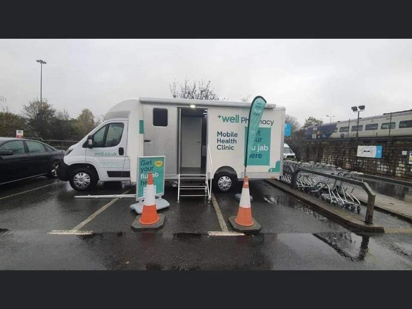 A Well Pharmacy mobile health clinic that says "Get your flu jab here"