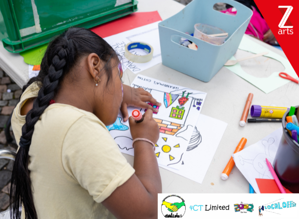 The photo shows a girl colouring a sheet with an illustration of a house. There are other crafts equipment, such as sellotape, markers, glue, and paper on the table. The upper-right side of the photo shows the Z-Arts logo. The lower-right side of the image shows the MPCF, 4CT, 2022 Our Year, and Local Offer logos, respectively.