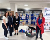 The photo shows the Early Years Communication and Language Team by their Baby Week 2024 stall at Manchester Central Library.