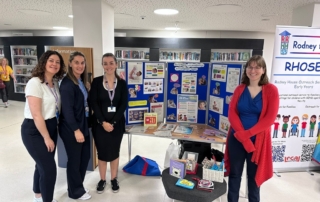 The photo shows the Early Years Communication and Language Team by their Baby Week 2024 stall at Manchester Central Library.