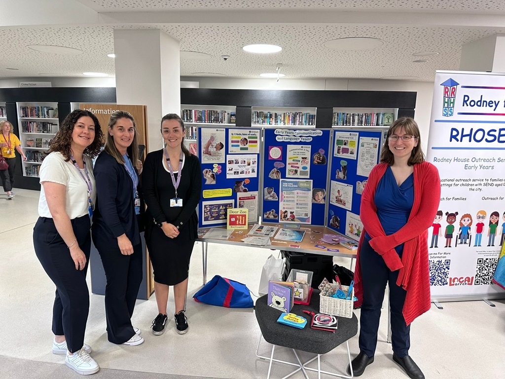 The photo shows the Early Years Communication and Language Team by their Baby Week 2024 stall at Manchester Central Library.