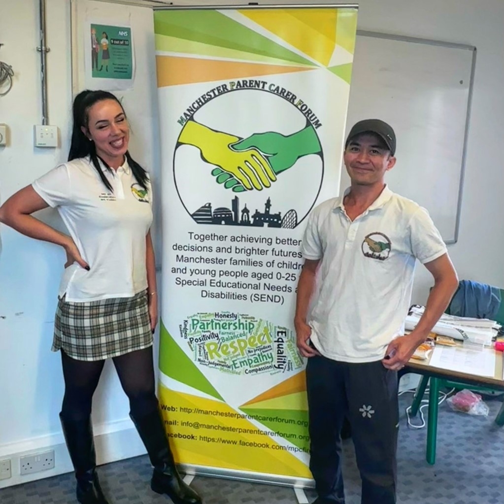 The photo shows Lia (left) and Jordan (right) from the MPCF team sandwiching the forum banner at the Local Offer Drop-in @ Manchester Settlement back in 9 July 2024.