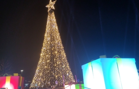 A big Christmas tree with yellow lights surrounded by huge light-up boxes.